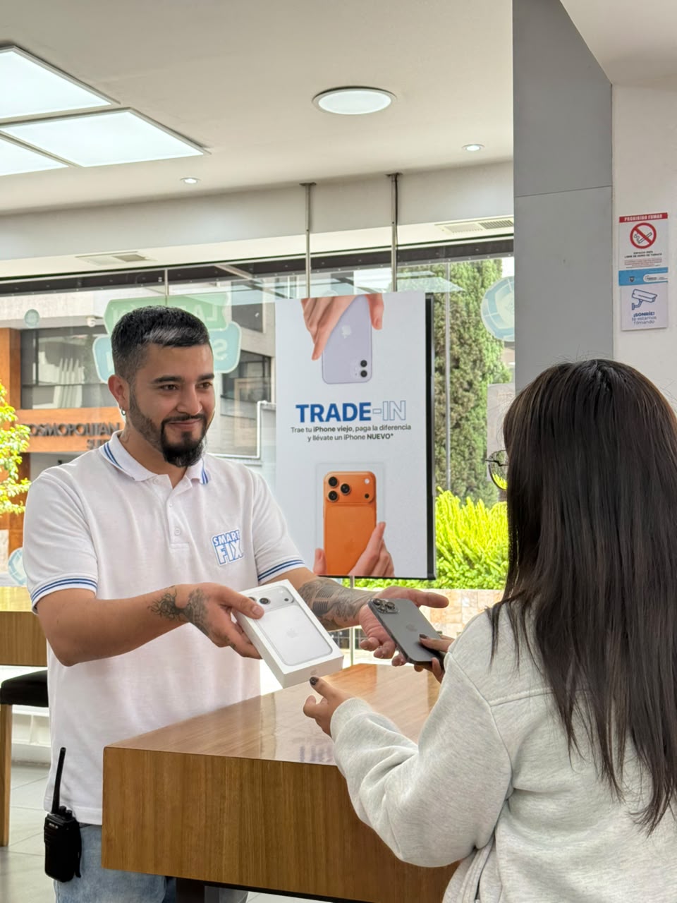 Asesor SmartFix entregando un iPhone nuevo a una clienta después de un Trade-In en tienda